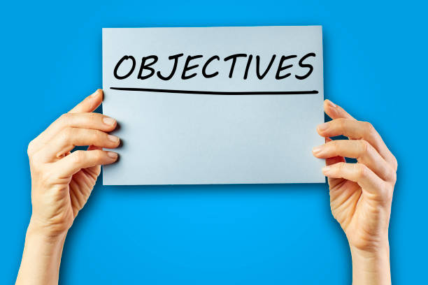 istock Woman's hands holding cardboard with the word Objectives on a blue background. 1316559109