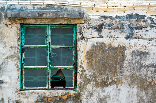 Window with broken glass of old abandoned and dilapidated stone house