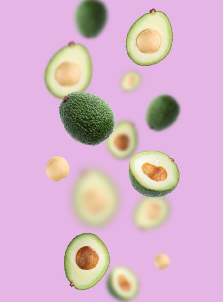 istock Pattern with ripe flying avocado halves on violet background. 1316559339