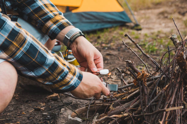 istock young strong man light a fire at camping site yellow tent on background 1316562223