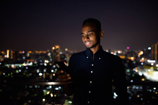 istock Happy African businessman outdoors at rooftop using phone at night 1316562843