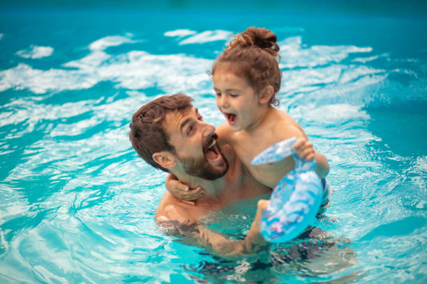 Father and son playing together in the swimming pool. Father and son playing together in the swimming pool. swimming protection stock pictures, royalty-free photos & images