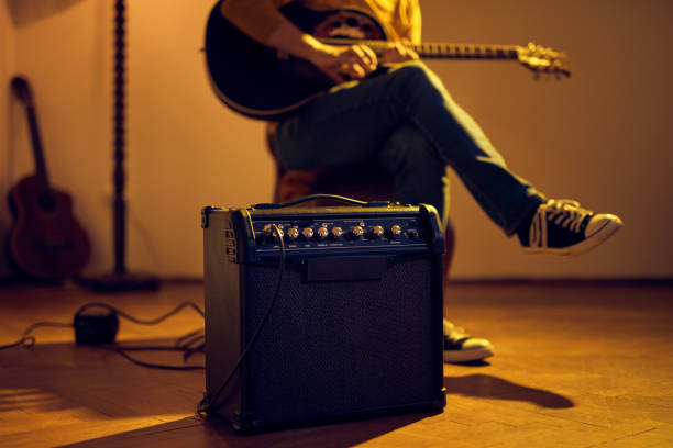 Male musician playing acoustic guitar on the amplifier in retro vintage room. Male musician playing acoustic guitar on the amplifier in retro vintage room. amplifier photos stock pictures, royalty-free photos & images