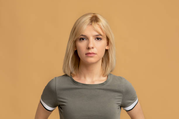 natürliche schönheit. porträt der blonden millennial frau mit ruhigem gesichtsausdruck, beige studio hintergrund - female color image human head studio shot stock-fotos und bilder