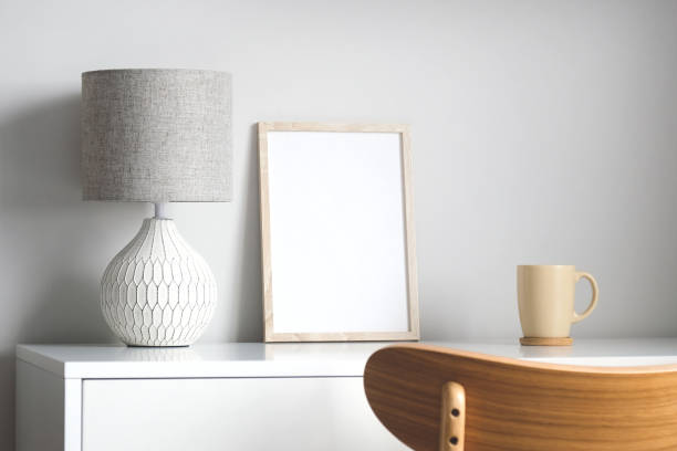 istock Empty wooden frame mockup on table with lamp and cup of coffee. Elegant feminine workspace. Scandinavian, nordic living room interior. 1316568921