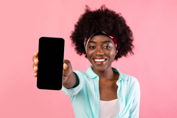 istock Black Bushy Lady Showing Phone Screen Over Pink Background 1316568977