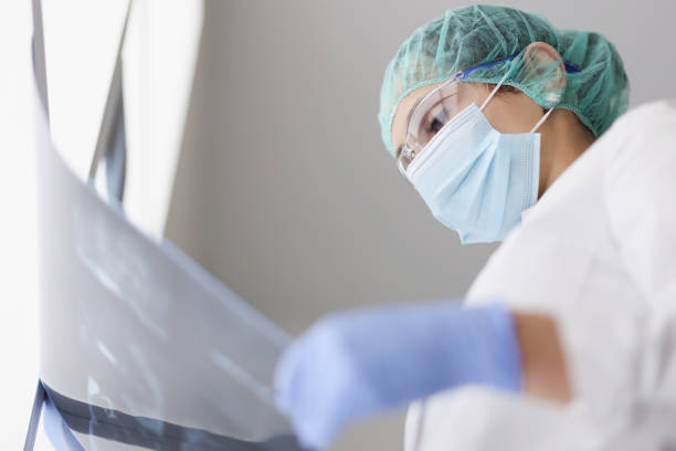 istock Doctor wearing protective mask and gloves examines an X-ray image 1316573392