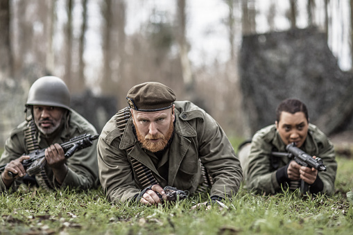 A redhead military male soldier, a black captain and female agent during an outdoor operation in the autumn