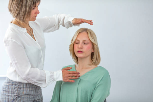 therapist giving reiki healing treatment to woman - hypnotist therapy alternative therapy alternative medicine imagens e fotografias de stock