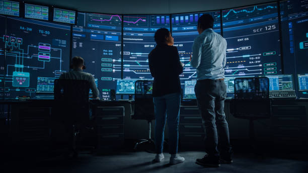 istock In the System Control Room Project Manager and IT Technical Engineer Have Discussion, they're surrounded by Multiple Monitors with Graphics. Big Monitor Shows Interactive Server Blockchain Info. 1316574100