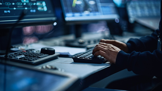 Primer plano de un especialista de oficina profesional que trabaja en el ordenador de escritorio en la sala de control de monitoreo tecnológico moderno con pantallas digitales. Administrador Escribiendo en el teclado y usando el ratón. photo