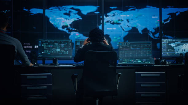 istock Diverse Multiethnic IT Technical Support Manager with Curved Hair Puts on Headphones. Monitoring Control Room Office with Big Digital Screens with Server Technical Blockchain Data. 1316574162