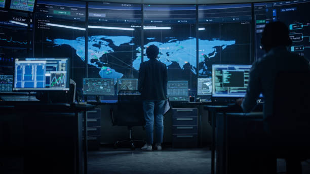 istock Diverse Multiethnic IT Technical Support Manager with Curved Hair Stands next to Workplace in Monitoring Control Room Office with Big Digital Screens with Server Technical Blockchain Data. 1316574171