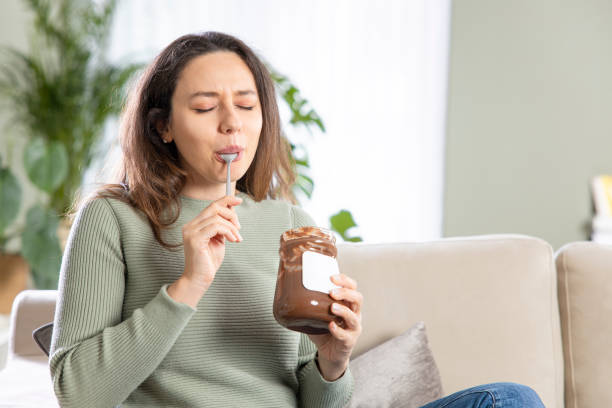 istock Young woman eating chocolate from a jar at home 1316577217