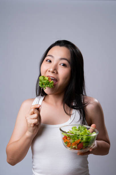 istock Asian woman eating salad isolated over white background. 1316577678