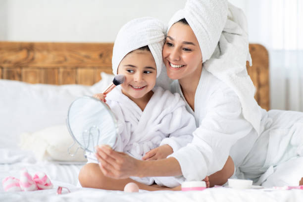 istock Cheerful little girl looking at mirror, putting blush on cheeks 1316578849