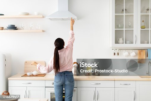 istock Woman select mode on cooking hood in kitchen 1316579417