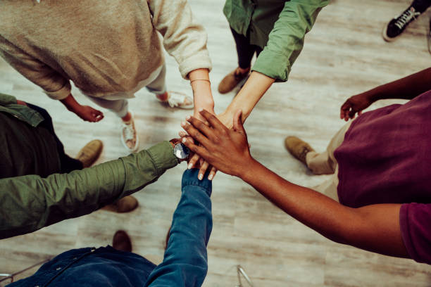 colegas de negocios juntando sus manos en la sala de oficinas, haciendo montones de manos mostrando unidad y trabajo en equipo - responsibility fotografías e imágenes de stock