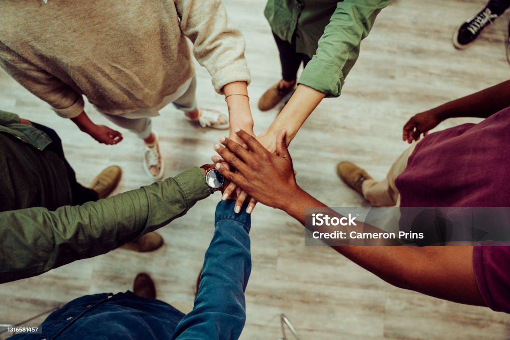 Business colleagues putting their hands together in office room, making piles of hands showing unity and team work Diverse group of business colleagues putting their hands together in office room, making piles of hands showing unity and team work before big presentation . High quality photo Handshake Stock Photo