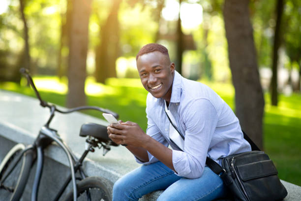 istock Happy black man with bicycle chatting on smartphone at urban park 1316582784