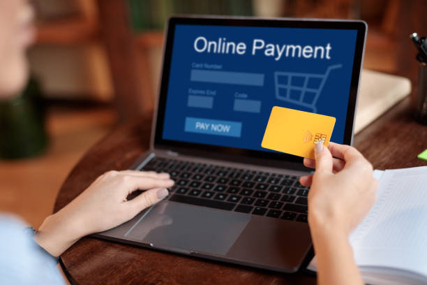 Woman using laptop and credit card, online payment concept Online Shopping, Payment System Concept. Over the shoulder view of unrecognizable woman holding credit card in hand and using laptop with online payment screen, typing on keyboard, creative image adult content payment processor stock pictures, royalty-free photos & images