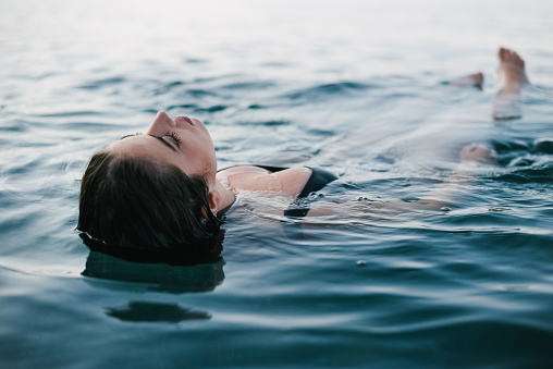 A beautiful woman emerges from the sea water. Blissful woman swimming in the sea in pleasure.