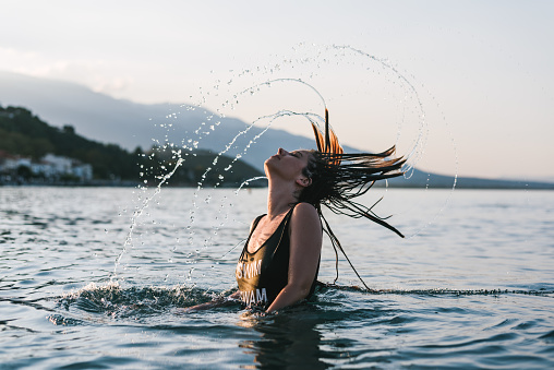 Girl in swimsuit splashing water with her hair