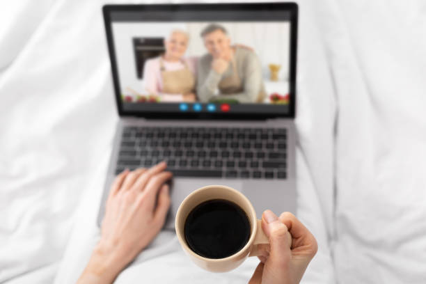 istock Unrecognizable Female Drinking Coffee In Bed And Making Video Call To Parents 1316585619