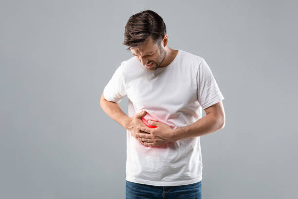 Man holding his right side, suffering from liver pain Middle-aged man holding his lightened with red right side, suffering from liver pain, grey studio background, copy space. Sad man having cirrhosis, rubbing his right side. Liver diseases concept hepatitis photos stock pictures, royalty-free photos & images