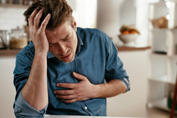 Portrait of man placing hands on the chest suffering from pain in the heart. Young man having a heart attack at home. Portrait of man placing hands on the chest suffering from pain in the heart. chest pain stock pictures, royalty-free photos & images
