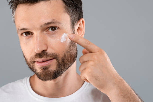 istock Closeup of bearded man applying face cream on grey 1316586158