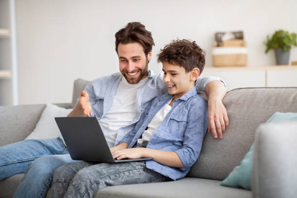 istock Young father and his preteen son using laptop together, looking at computer screen, making online shopping 1316586860