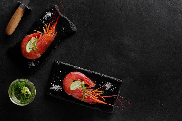 istock Cooked prawns with condiments and shrimp knife on black background 1316587356