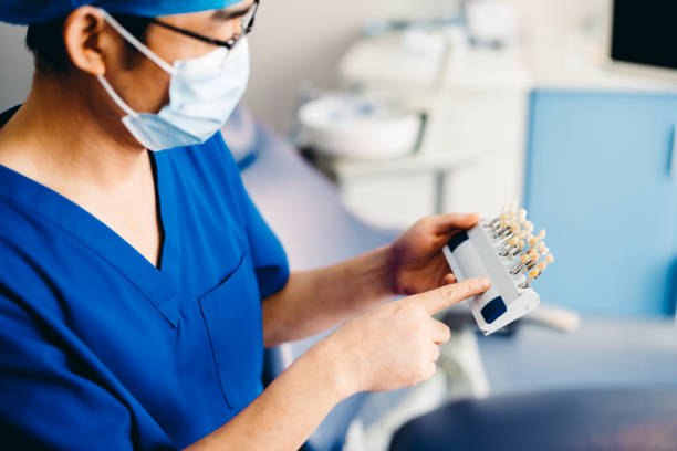 istock Asian dentist holding dental tooth shade guide. 1316588627