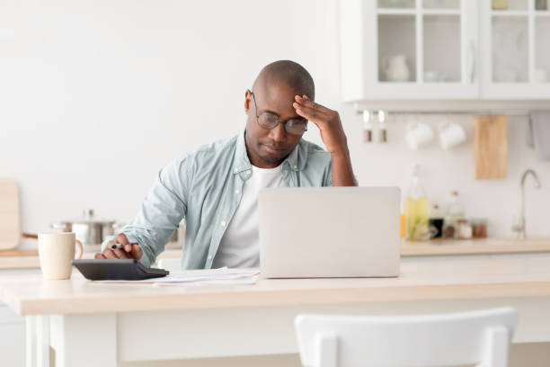 istock Stressed mature black man using calculator and laptop computer, calculating taxes, checking monthly expenses 1316589864