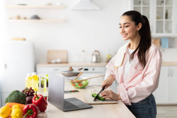 istock Woman cooking salad and using laptop and kitchen 1316590153