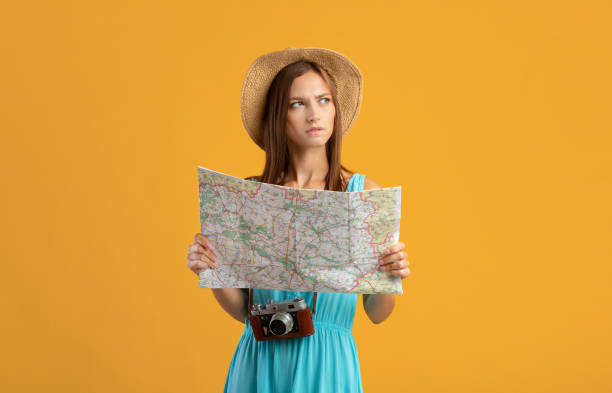 istock Pensive young woman with camera holding city map 1316591619