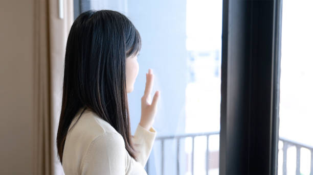 istock Young Asian woman looking through the window at home 1316593036