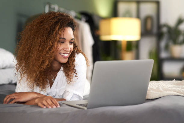 istock Shot of a young woman using her laptop while lying on her bed 1316595100