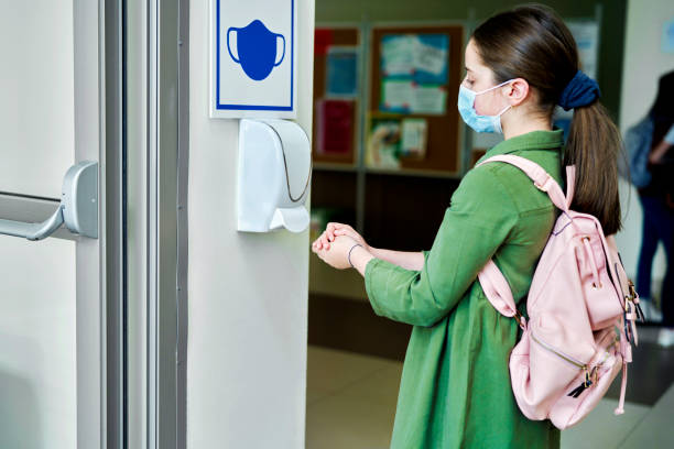 istock Schoolgirl wearing protective face masks disinfect their hands 1316595703