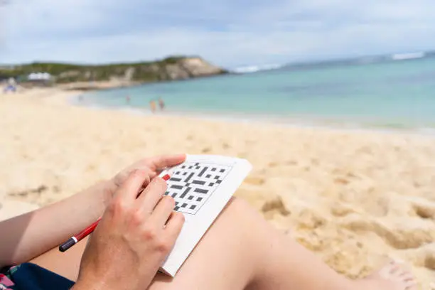 Sudoku puzzle on a sandy beach with clear blue water in the background