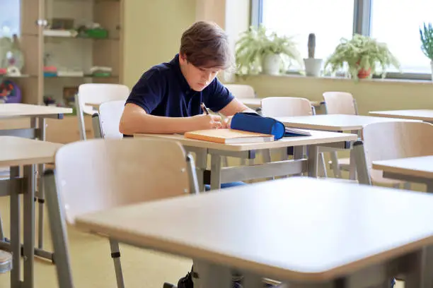 One student sitting and learning alone in empty classroom