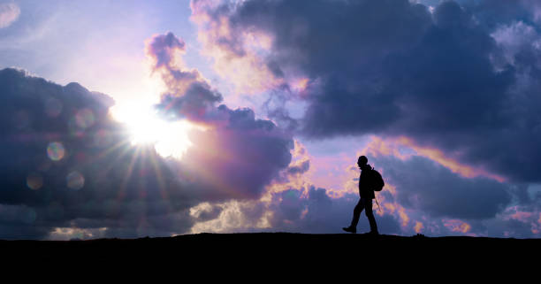 istock Mountaineer walking with the sun through the clouds at sunset. 1316597751