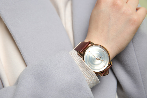 Woman in grey jacket with luxury wristwatch, closeup