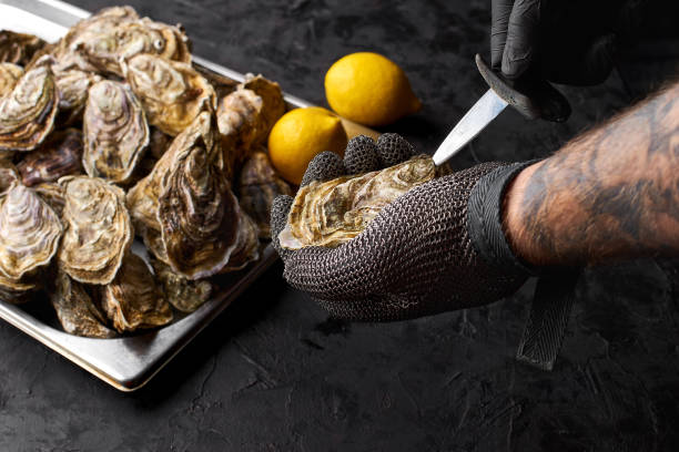 foco seletivo à mão prepare ostras frescas na bancada de frutos do mar no mercado. - prepared oysters prepared shellfish shucked seafood - fotografias e filmes do acervo