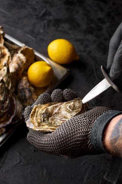 foco seletivo à mão prepare ostras frescas na bancada de frutos do mar no mercado. - prepared oysters prepared shellfish shucked seafood - fotografias e filmes do acervo