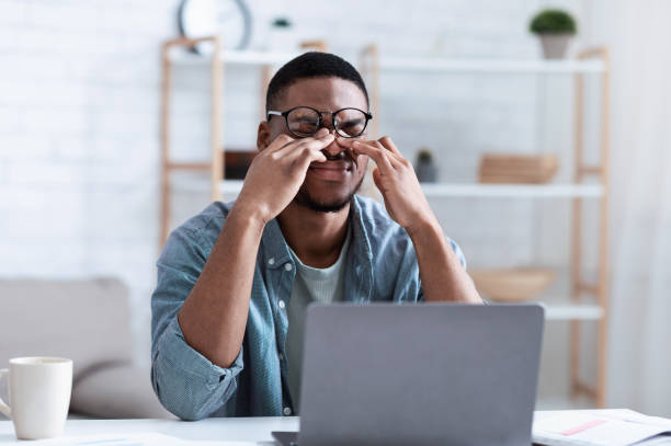 homme africain massant des yeux après travail sur l’ordinateur au lieu de travail - dry photos et images de collection