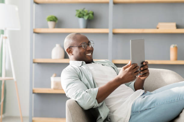 istock African american man reading e-book on digital tablet or browsing internet, enjoying weekend and resting on armchair 1316602735
