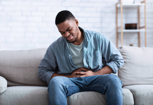 istock Black Guy Having Painful Stomachache Touching Aching Stomach Sitting Indoors 1316604347