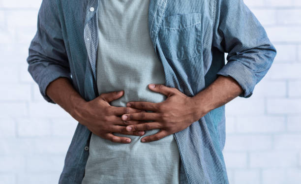 Black Guy Touching Aching Abdomen Having Stomachache, Gray Background, Cropped Unrecognizable Black Guy Touching Aching Abdomen Having Painful Stomachache Standing Over Gray Studio Background. African Man Suffering From Stomach Inflammation. Gastritis And Abdomen Pain. Cropped stomach stock pictures, royalty-free photos & images